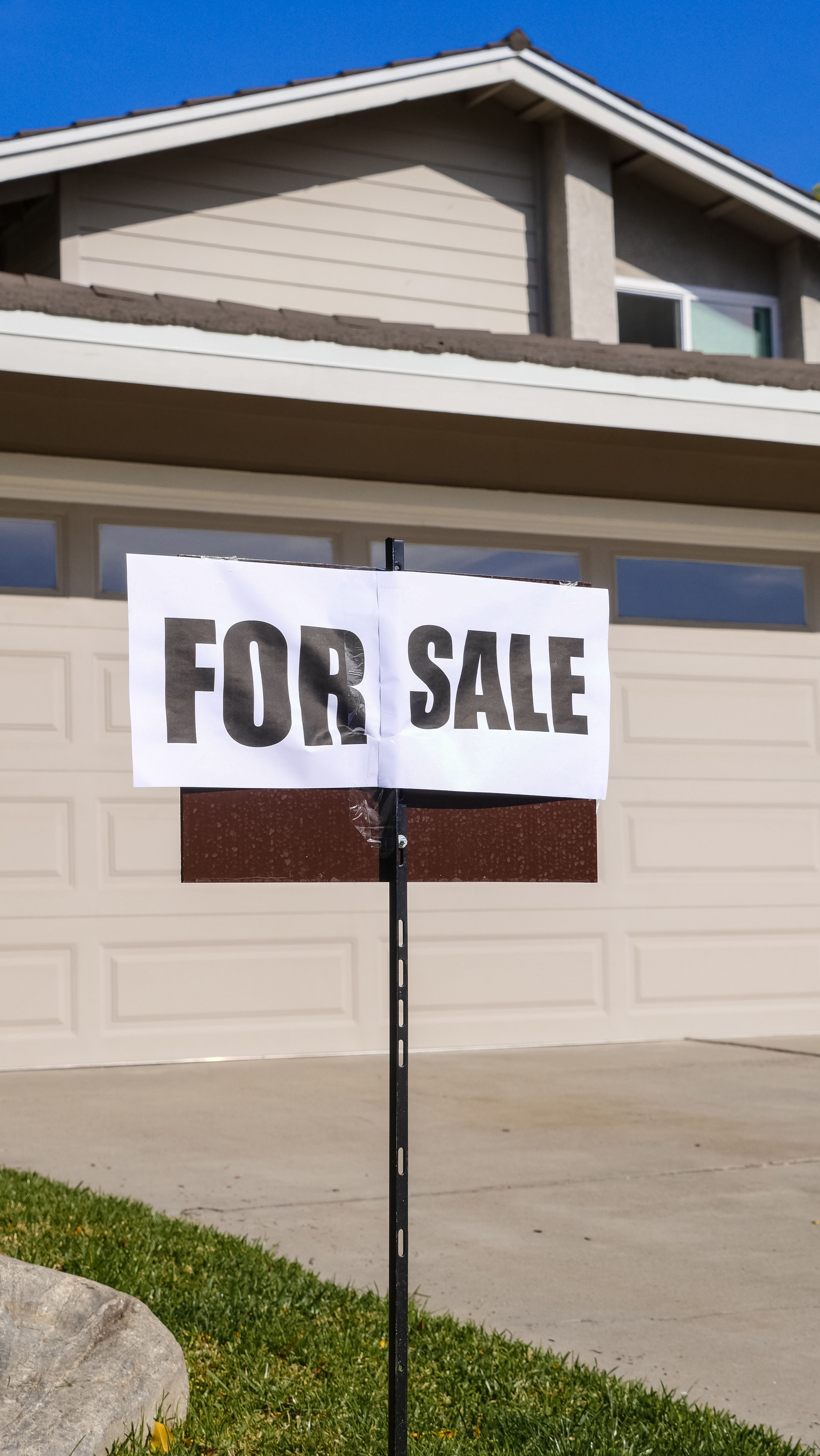 A for-sale-by-owner yard sign in front of a house