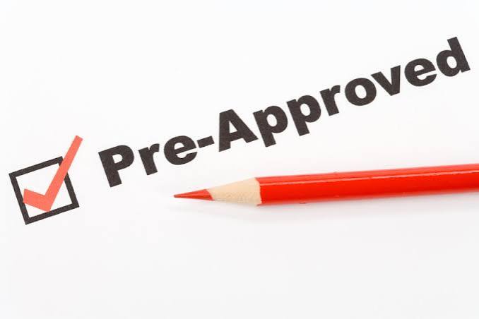 A mortgage pre-approval letter on a desk next to a home